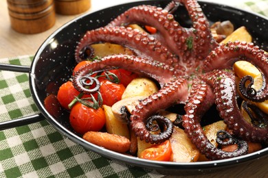 Photo of Fried octopus with vegetables in pan on wooden table, closeup