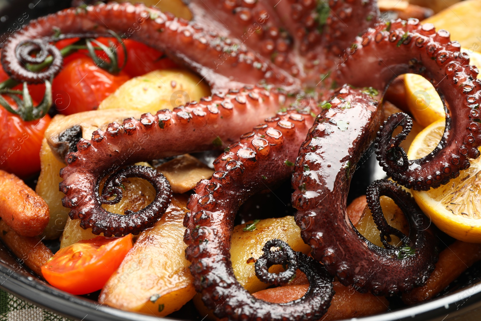 Photo of Fried octopus with lemon and vegetables in pan, closeup