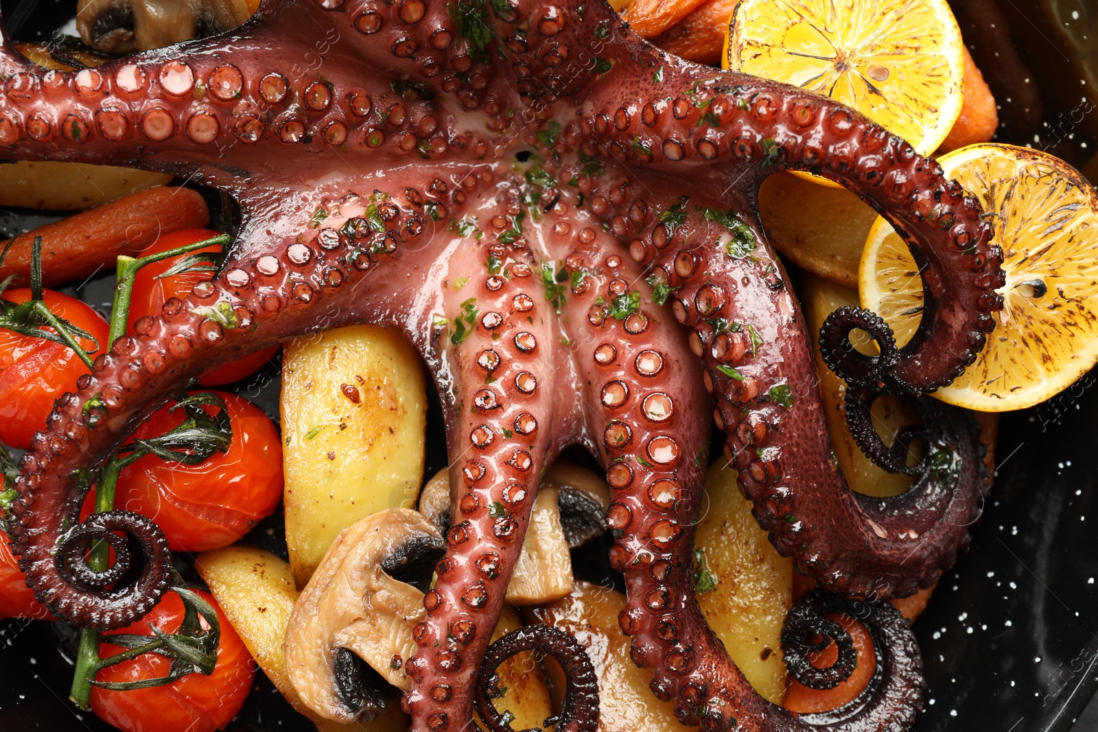 Photo of Fried octopus with lemon, mushrooms and vegetables in pan, top view