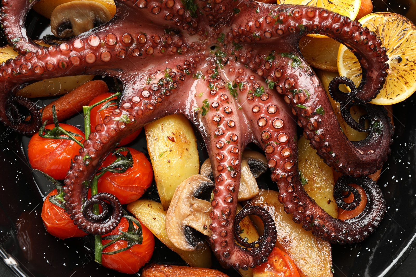 Photo of Fried octopus with lemon, mushrooms and vegetables in pan, top view