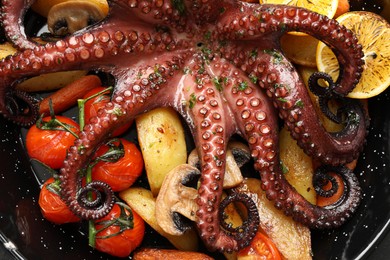 Photo of Fried octopus with lemon, mushrooms and vegetables in pan, top view