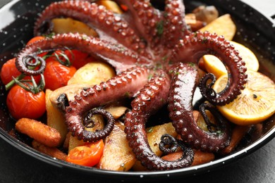 Photo of Fried octopus with lemon and vegetables on grey table, closeup