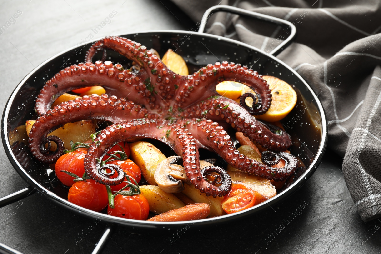 Photo of Fried octopus with mushroom and vegetables on grey textured table, closeup