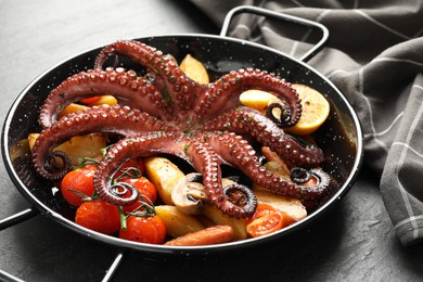 Photo of Fried octopus with mushroom and vegetables on grey textured table, closeup