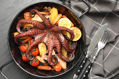 Photo of Fried octopus with mushrooms, lemon and vegetables on grey textured table, flat lay