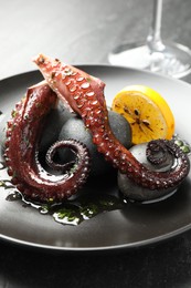 Photo of Fried octopus with herb sauce and lemon served on grey table, closeup