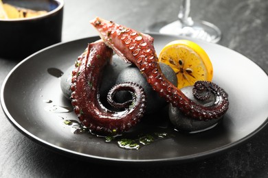 Fried octopus with herb sauce and lemon served on grey textured table, closeup