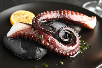 Photo of Fried octopus with herb sauce and lemon served on table, closeup