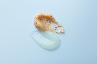 Photo of Smears of body scrubs on light blue background, closeup