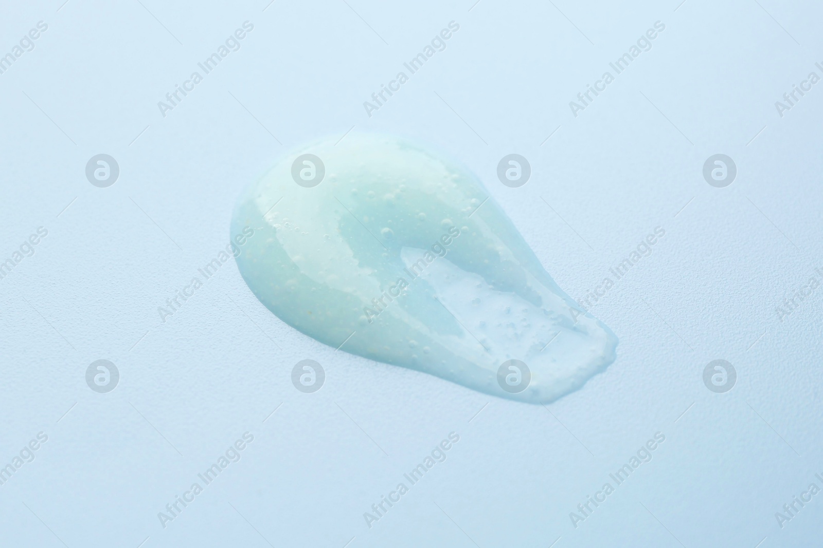 Photo of Smear of body scrub on light blue background, closeup