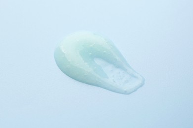 Photo of Smear of body scrub on light blue background, closeup