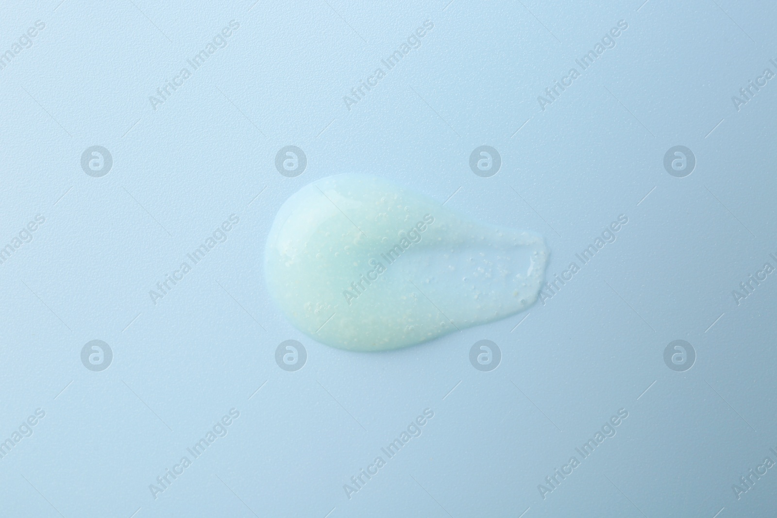 Photo of Smear of body scrub on light blue background, top view