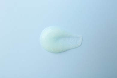 Photo of Smear of body scrub on light blue background, top view