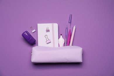 Photo of Pencil case and different stationery on purple background, flat lay