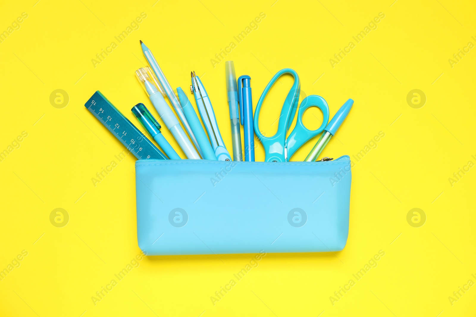 Pencil case and different stationery on yellow background, flat lay Photo of Pencil case and different stationery on yellow background, flat lay