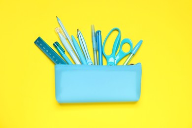 Photo of Pencil case and different stationery on yellow background, flat lay
