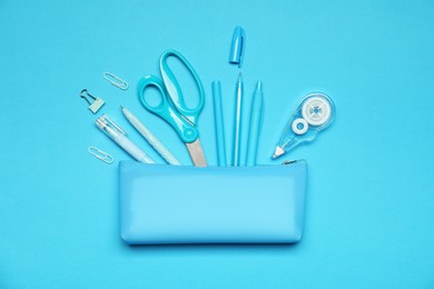 Photo of Pencil case and different stationery on light blue background, flat lay