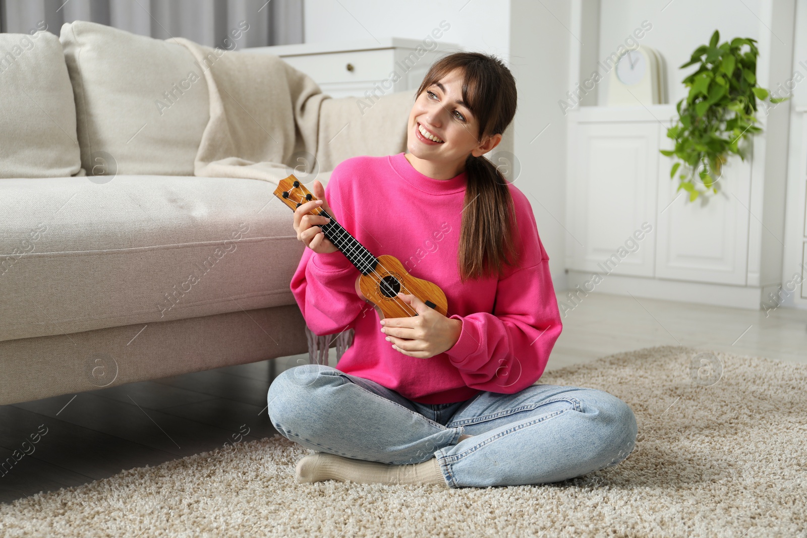 Photo of Happy woman playing ukulele on floor at home