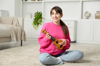 Photo of Happy woman playing ukulele on floor at home