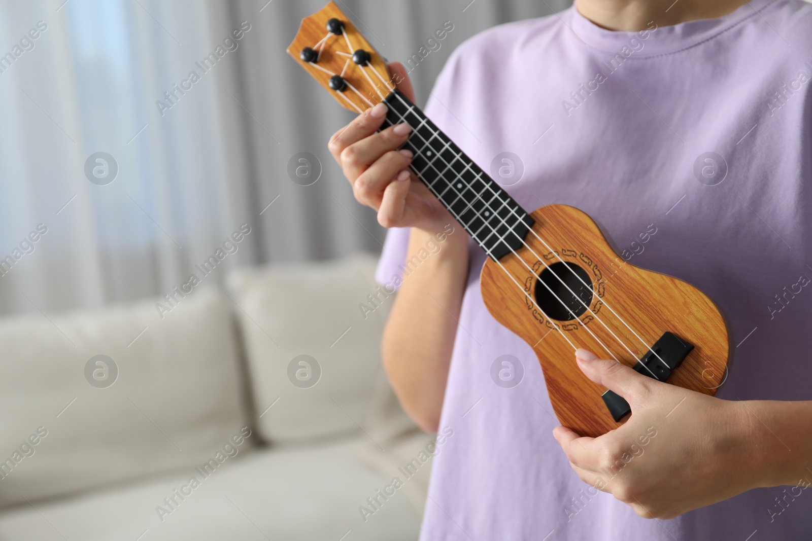 Photo of Woman playing ukulele at home, closeup. Space for text