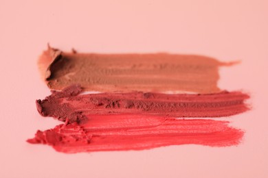 Photo of Samples of bright lipsticks on beige background, closeup