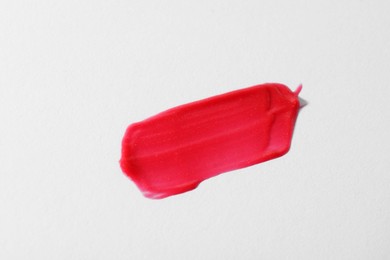 Photo of Sample of red lipgloss on light grey background, top view