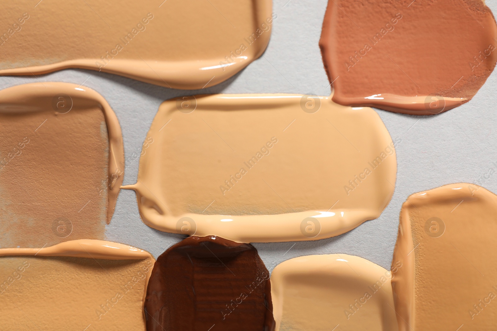 Photo of Samples of different foundation on light grey background, top view