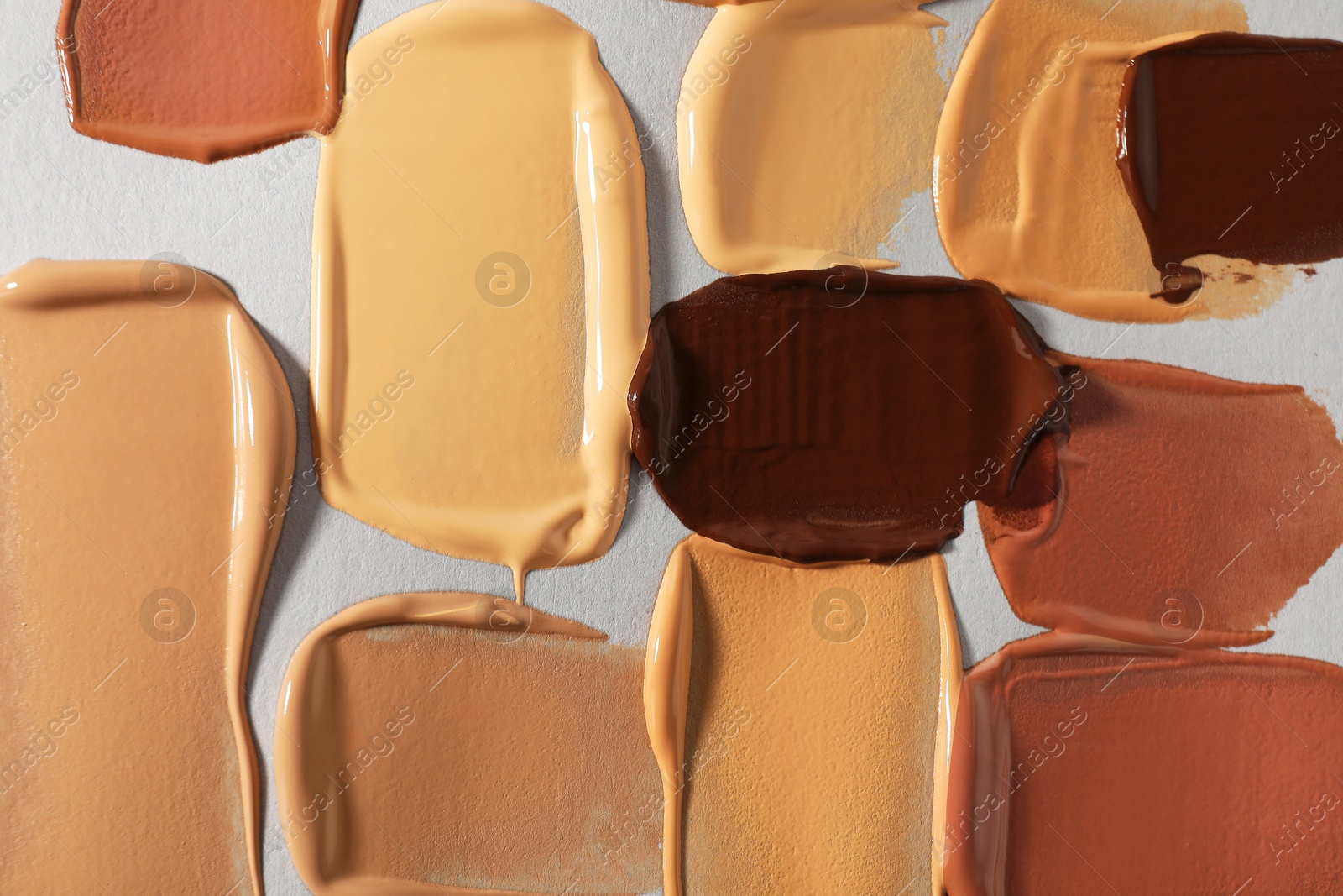 Photo of Samples of different foundation on light grey background, top view