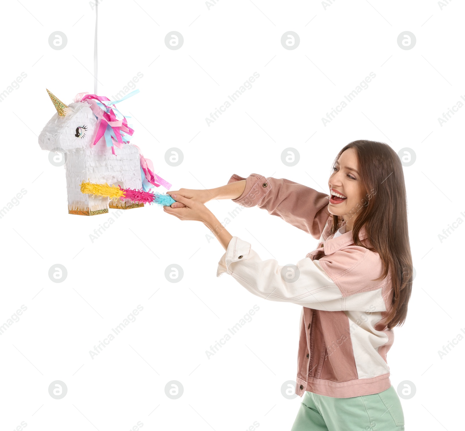 Photo of Happy woman breaking unicorn shaped pinata with stick isolated on white