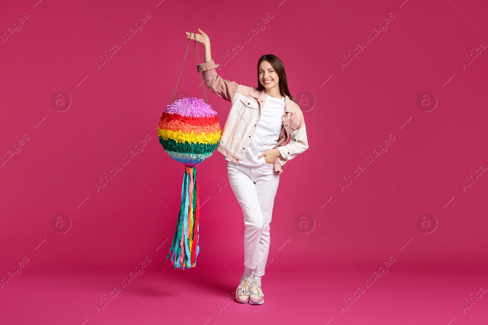 Photo of Happy woman with colorful pinata on pink background