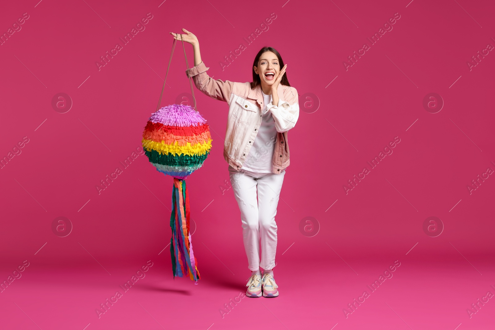 Photo of Happy woman with colorful pinata on pink background