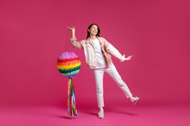 Photo of Happy woman with colorful pinata on pink background