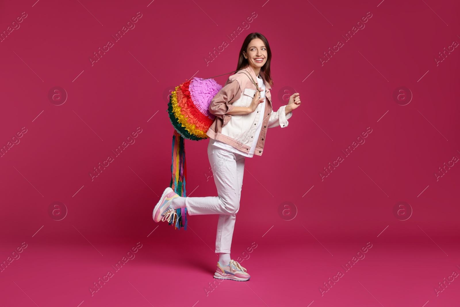 Photo of Happy woman with colorful pinata on pink background