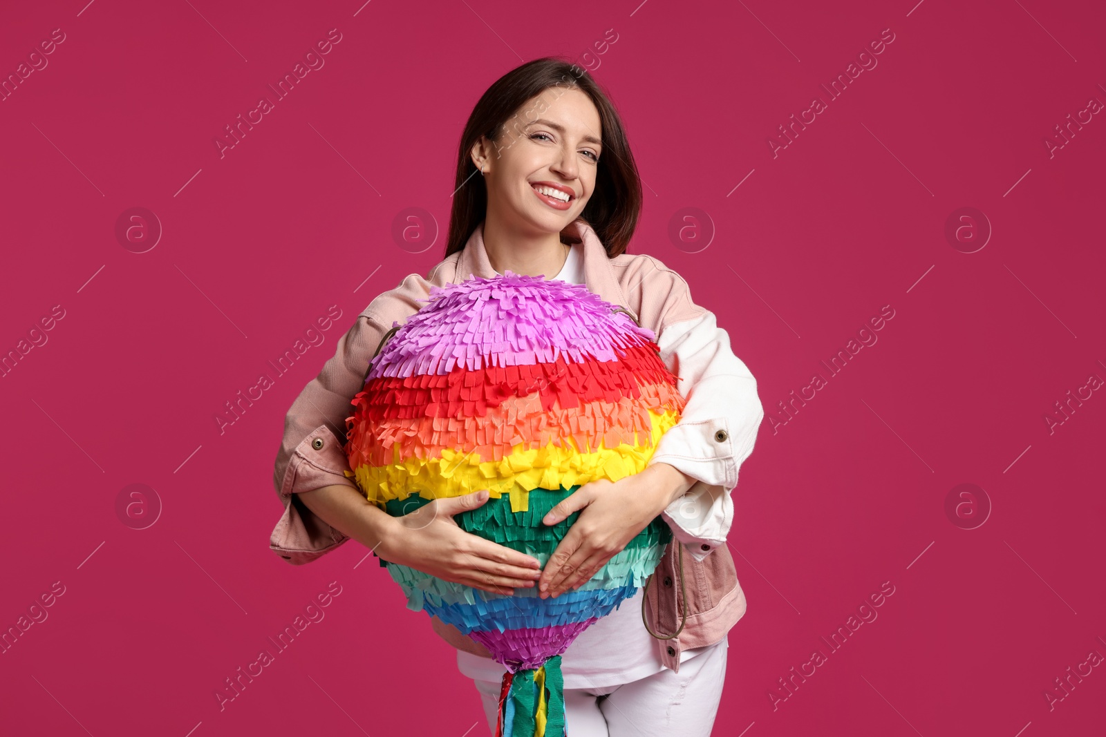 Photo of Happy woman with colorful pinata on pink background