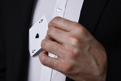 Illusionist hiding playing card behind jacket lapel, closeup