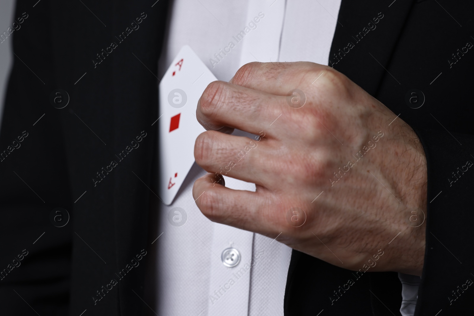 Photo of Illusionist hiding playing card behind jacket lapel, closeup