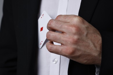 Photo of Illusionist hiding playing card behind jacket lapel, closeup