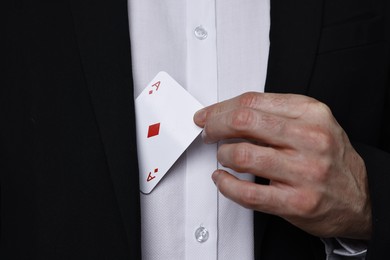 Photo of Illusionist hiding playing card behind jacket lapel, closeup