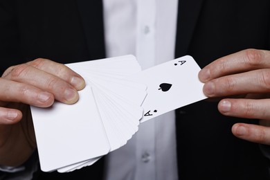 Photo of Illusionist with playing cards on grey background, closeup