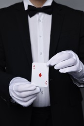 Photo of Illusionist with playing card on grey background, closeup