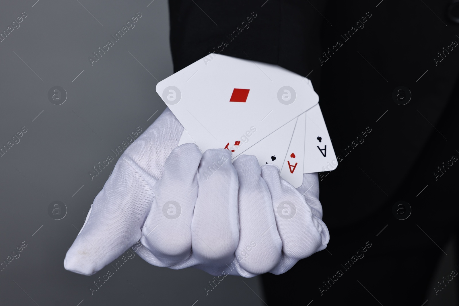 Photo of Illusionist taking playing cards out of sleeve on grey background, closeup