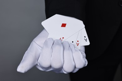 Photo of Illusionist taking playing cards out of sleeve on grey background, closeup