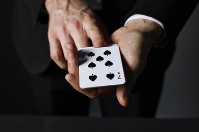 Illusionist with playing cards at black table, closeup