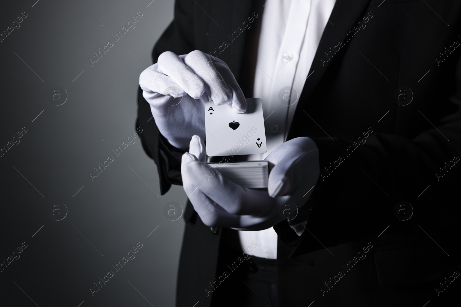 Photo of Illusionist shuffling playing cards on grey background, closeup