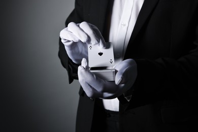 Photo of Illusionist shuffling playing cards on grey background, closeup