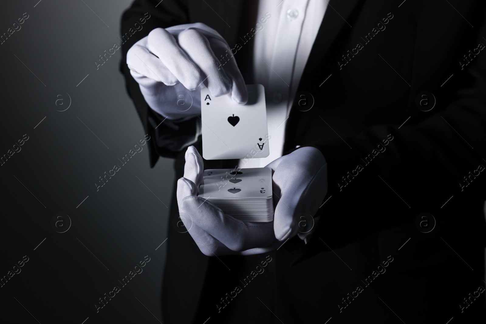 Photo of Illusionist shuffling playing cards on grey background, closeup