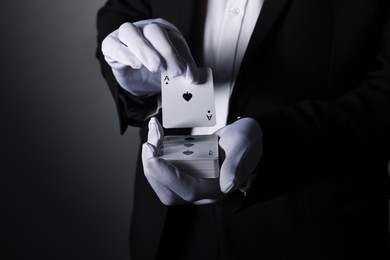 Photo of Illusionist shuffling playing cards on grey background, closeup