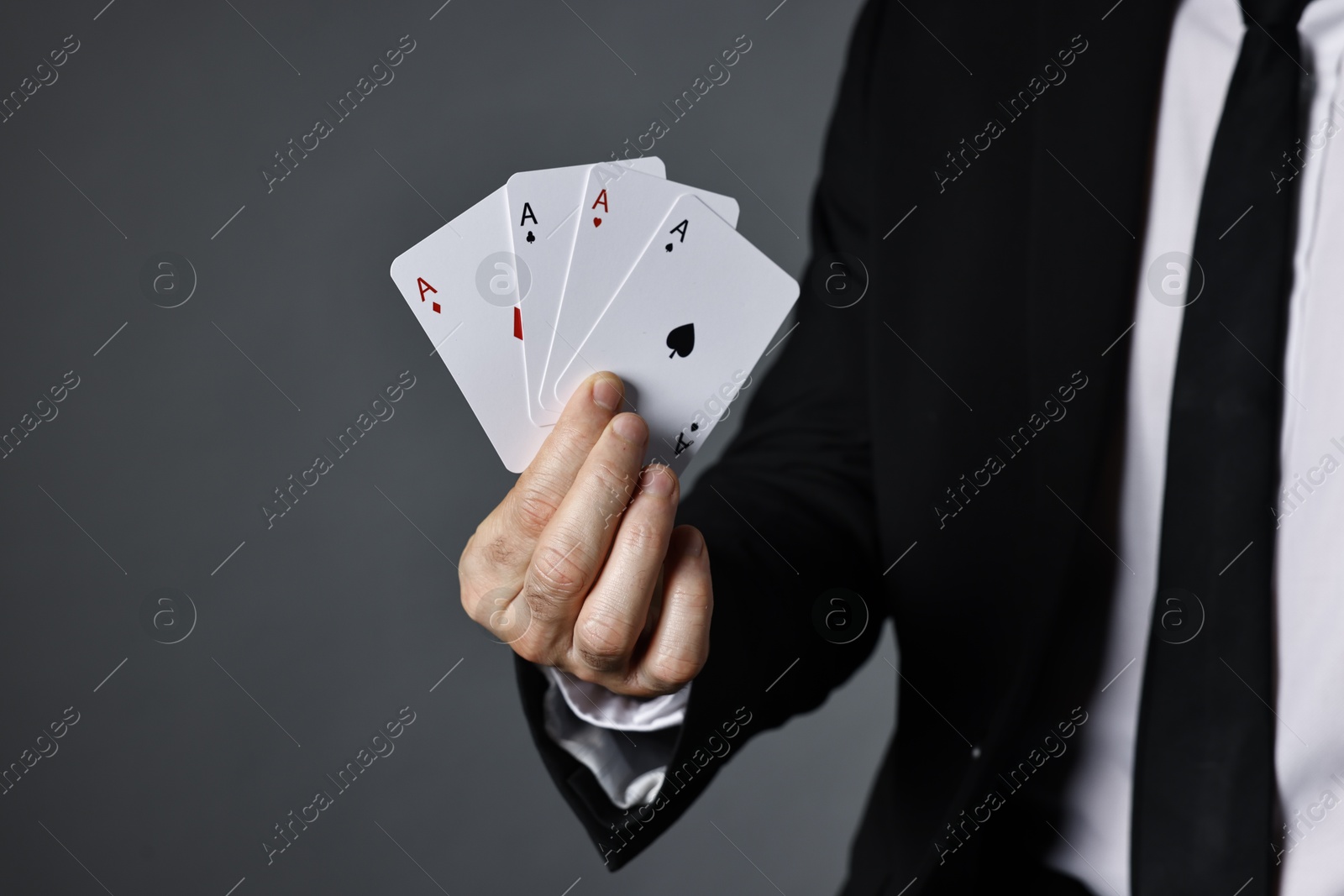 Photo of Illusionist with playing cards on grey background, closeup