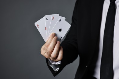 Photo of Illusionist with playing cards on grey background, closeup