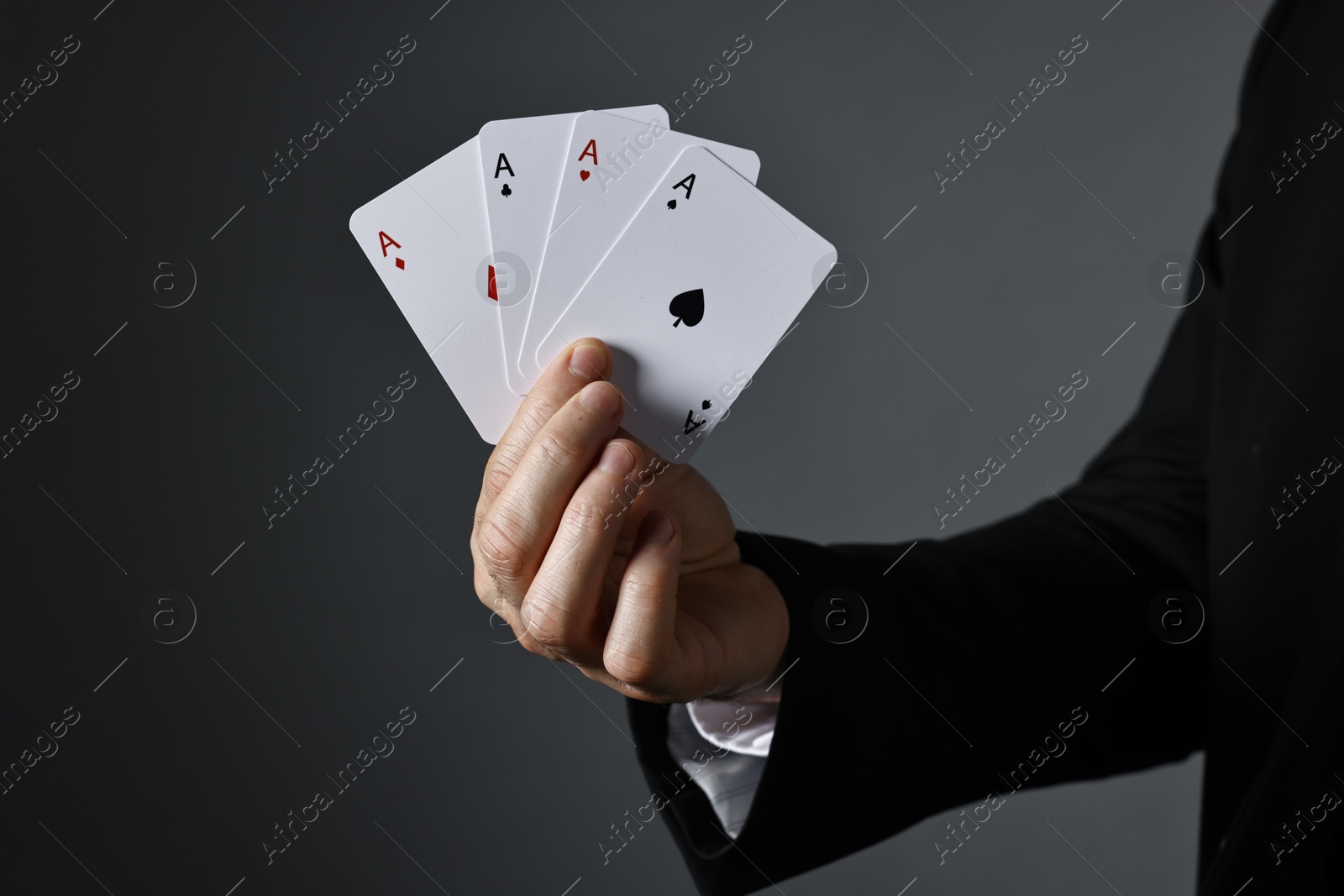 Photo of Illusionist with playing cards on grey background, closeup